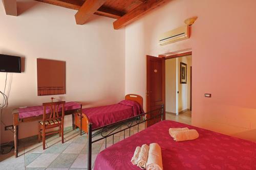 a room with two beds and a table and a tv at Bed And Breakfast Sciarammola in Patti
