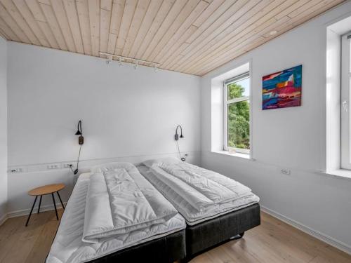 a bed in a white room with a wooden ceiling at Holiday Home Amma - 21km from the sea by Interhome in Bredebro