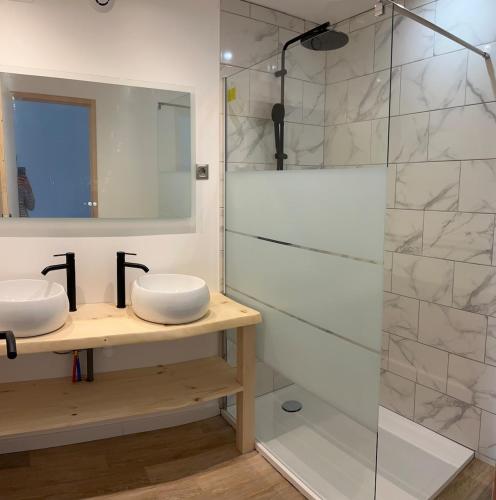 a bathroom with two sinks and a shower at Hébergement La Fontaine in La Coudre