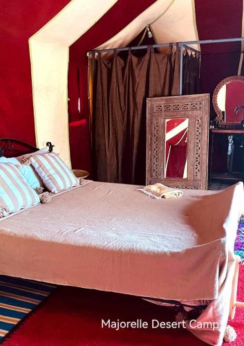 a bedroom with a bed with a mirror on it at Majorelle Desert Camp in Zagora