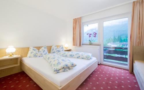 a bedroom with a bed and a large window at Ferienwohnung Pension Tirol in Bichlbach