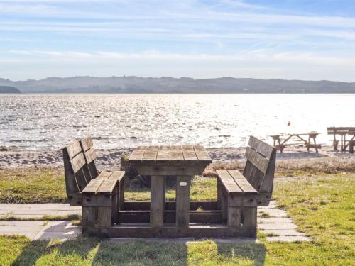 a picnic table and benches next to the water at Holiday Home Gyrid - 150m from the sea by Interhome in Rønde