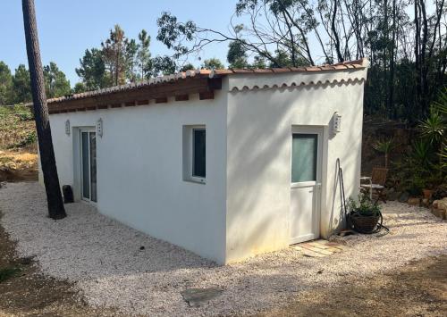 a small white building with a door in a yard at Casinha Ninho da Mãe in Rogil