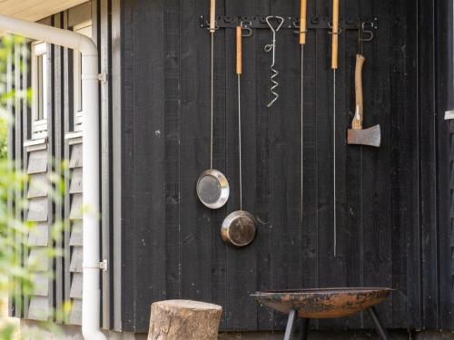 a black wall with pots and pans and a wheelbarrow at Holiday Home Sira - 350m from the sea by Interhome in Spodsbjerg