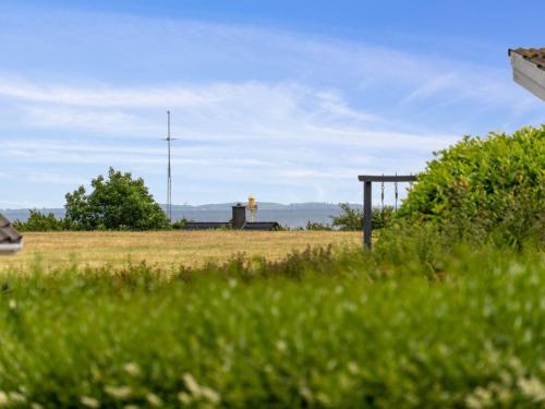 a field of grass with a building in the background at Holiday Home Sira - 350m from the sea by Interhome in Spodsbjerg