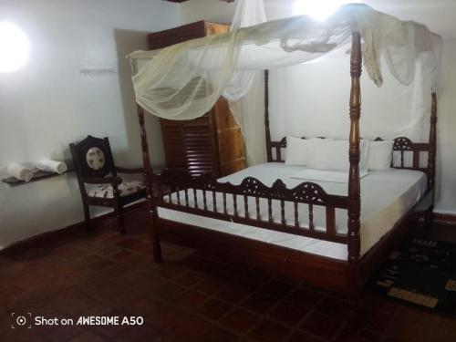 a bedroom with a canopy bed and two chairs at Haki Villas A in Gatunga