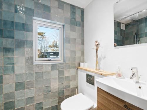 a bathroom with a toilet and a sink and a window at Holiday Home Alica - 200m from the sea by Interhome in Neksø