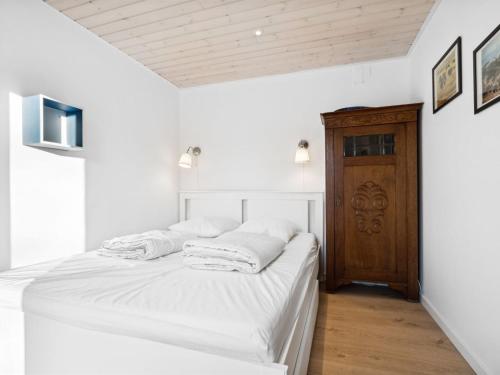 a white bedroom with a bed with white sheets at Holiday Home Alica - 200m from the sea by Interhome in Neksø