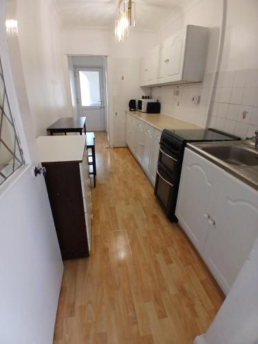 a kitchen with white cabinets and a wooden floor at Rose Cottage-4 BED HOUSE FOR CONTRACTORS & FAMILIES Close to M6, J10-NO PARTIES ALLOWED in Walsall
