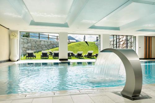 a swimming pool with a waterfall in a building at Hotel Lac Salin Spa & Mountain Resort in Livigno