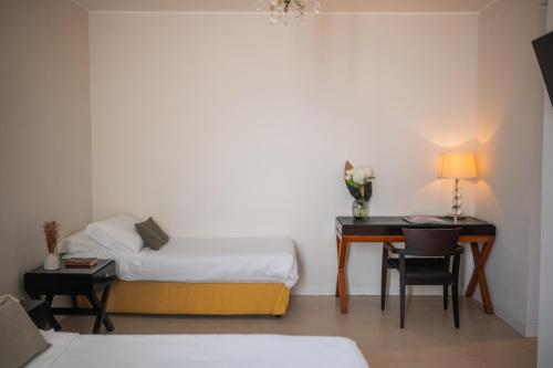 a bedroom with a bed and a desk and a table at Hotel Palazzo Cavalieri in Siracusa