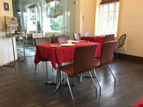 a dining room with a table and chairs with red table cloth at The Harrington Residency in Kolkata