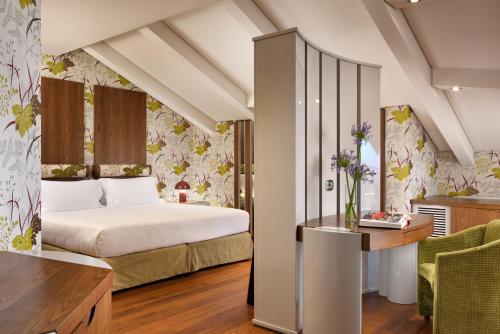 a bedroom with a bed and a desk in a room at Il Boscareto Resort & Spa in Serralunga d'Alba
