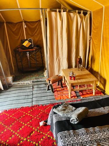 a room with a tent with a table and a rug at Majorelle Desert Camp in Zagora