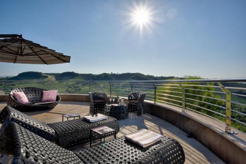 a deck with chairs and tables and an umbrella at Il Boscareto Resort & Spa in Serralunga d'Alba