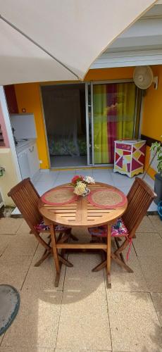 a wooden table with two chairs around it at Studios Becassine et Tangara Domaine de Belfond St Anne in Sainte-Anne