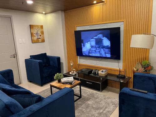 a living room with two blue chairs and a flat screen tv at Skyview 2BR at Grass in Manila