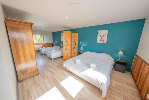 Un dormitorio con dos camas y una pared azul. en L'envolée Sauvage, en Saint-Nectaire