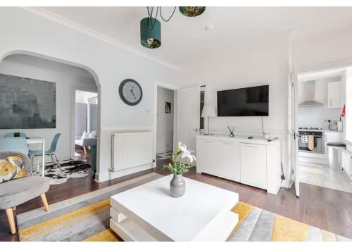 a white living room with a white couch and a tv at Elegant Flat in a Serene Edinburgh Neighbourhood in Edinburgh
