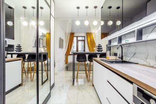 a kitchen with white cabinets and black bar stools at Rodos ArCadia Apartments in Odesa