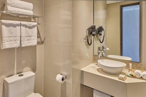 a bathroom with a toilet and a sink and a mirror at Belmont Hotel Boracay near Newcoast Beach in Boracay