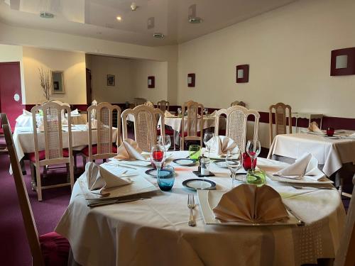 a dining room with tables and chairs with white tablecloths at Logis Hôtel & Restaurant - Le Bretagne in Sillé-le-Guillaume