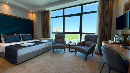 a bedroom with a bed and two chairs and a table at Alsancak Prime Hotel Konya in Yazır
