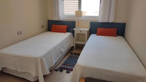 Dos camas en una habitación pequeña con dos almohadas naranjas. en Vista Bahia, en Porís de Abona