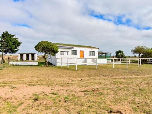 a white house with a fence in a field at Wiggins Self Catering in Jacobs Bay