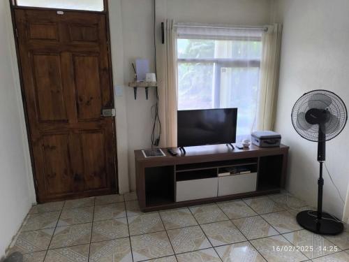 Una sala de estar con televisión y ventilador y una puerta. en Pacayitas El Camino House, en Turrialba