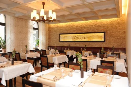 um restaurante com mesas e cadeiras brancas e um lustre em Hotel-Restaurant "Zum Alten Fritz" em Mayen