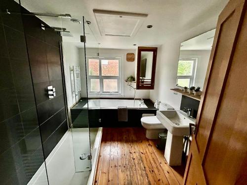 a bathroom with a tub and a toilet and a sink at Nomi Homes - Okehampton Place - Exeter - Sleeps 7 in Exeter