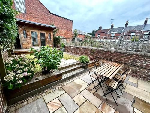a patio with two chairs and a wooden bench at Nomi Homes - Okehampton Place - Exeter - Sleeps 7 in Exeter