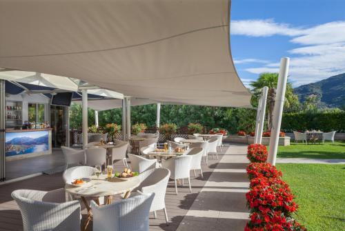 a restaurant with white tables and white chairs and flowers at Hotel Savoy Palace - Tonelli Hotels in Riva del Garda