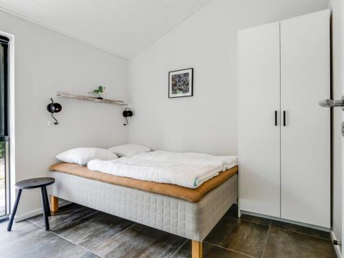 a bed in a room with a white wall at Holiday Home Sighvat - 300m from the sea by Interhome in Læsø