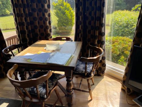 a wooden table with chairs in a room with a window at Bellfield Country Suites in Masham