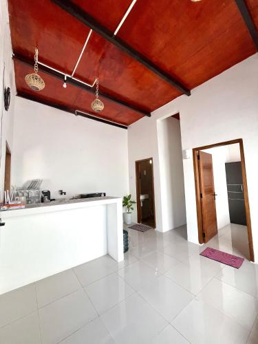 a kitchen with white walls and a wooden ceiling at The Griya Masz Guesthouse 2 in Kuta Lombok