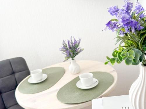 a table with two cups and a vase with purple flowers at Fährhaus Brunsbüttel in Brunsbüttel