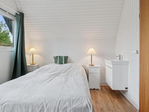 a white bedroom with a bed and a sink at Holiday Home Hildegunda - 280m from the sea by Interhome in Neksø