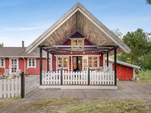 a red house with a white fence in front of it at Holiday Home Stig - 1km from the sea by Interhome in Sæby