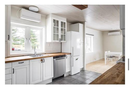 a white kitchen with white cabinets and a table at Lake house in Stockholm