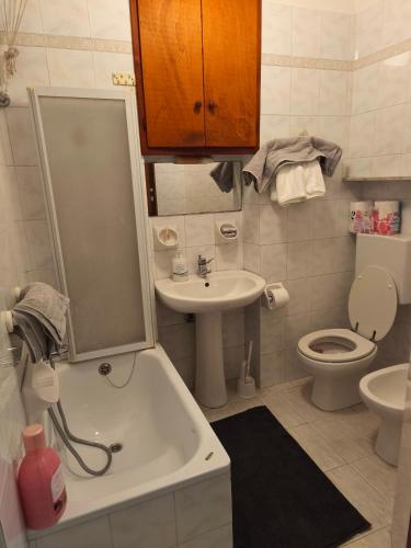 a bathroom with a sink and a toilet and a tub at Regina Margherita Apartment in Rocchetta Ligure