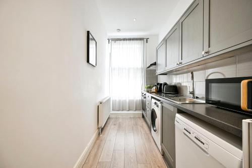 una cucina con mobili bianchi e pavimento in legno di Superb 1bed Ealing Apartment- Steps to Tube & City Attractions a Ealing
