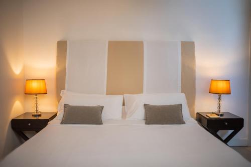 a bedroom with a large white bed with two lamps at Hotel Palazzo Cavalieri in Siracusa