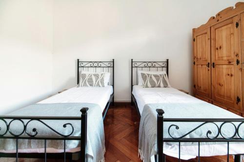 two beds in a room with white walls and wooden floors at Almost Paradise by Quokka 360 - flat with a view of Lake Como in Brunate
