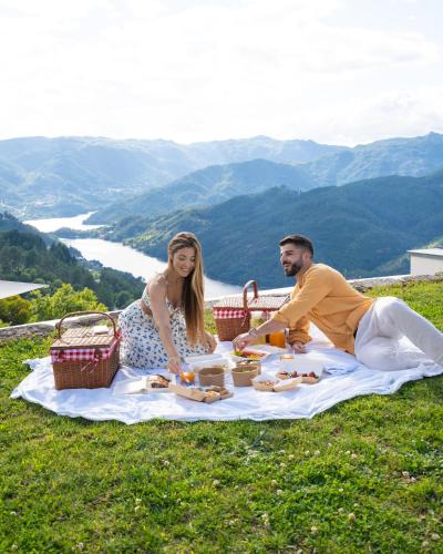a man and a woman sitting on a picnic blanket at Pousadela Village & Spa in Vieira do Minho
