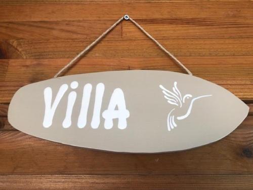 a white sign hanging on a wooden table at Villa Tigo T3 Colibri in Sainte-Luce
