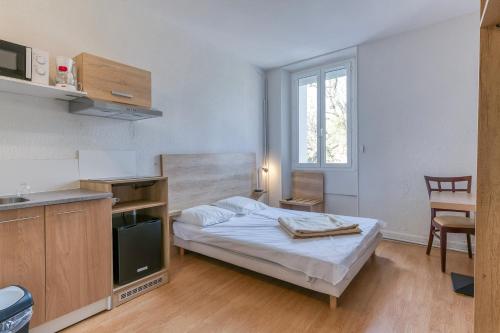 a small bedroom with a bed and a kitchen at Logis Belledonne in Arvillard
