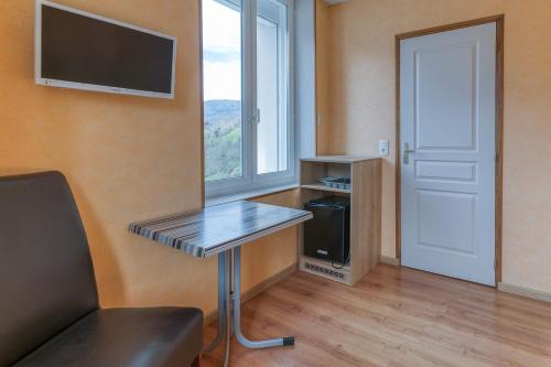 a room with a desk and a tv and a window at Logis Belledonne in Arvillard