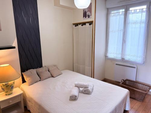ムランにあるCharmant appartement au cœur de Melunのタオルが敷かれた白いベッドのある寝室